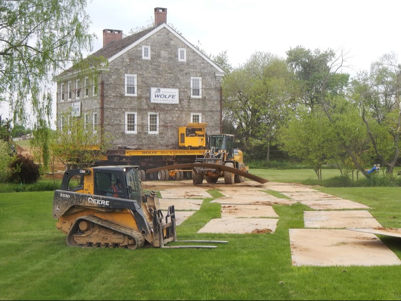 Loaders lay a path of steel plate for a large stone house that is being moved